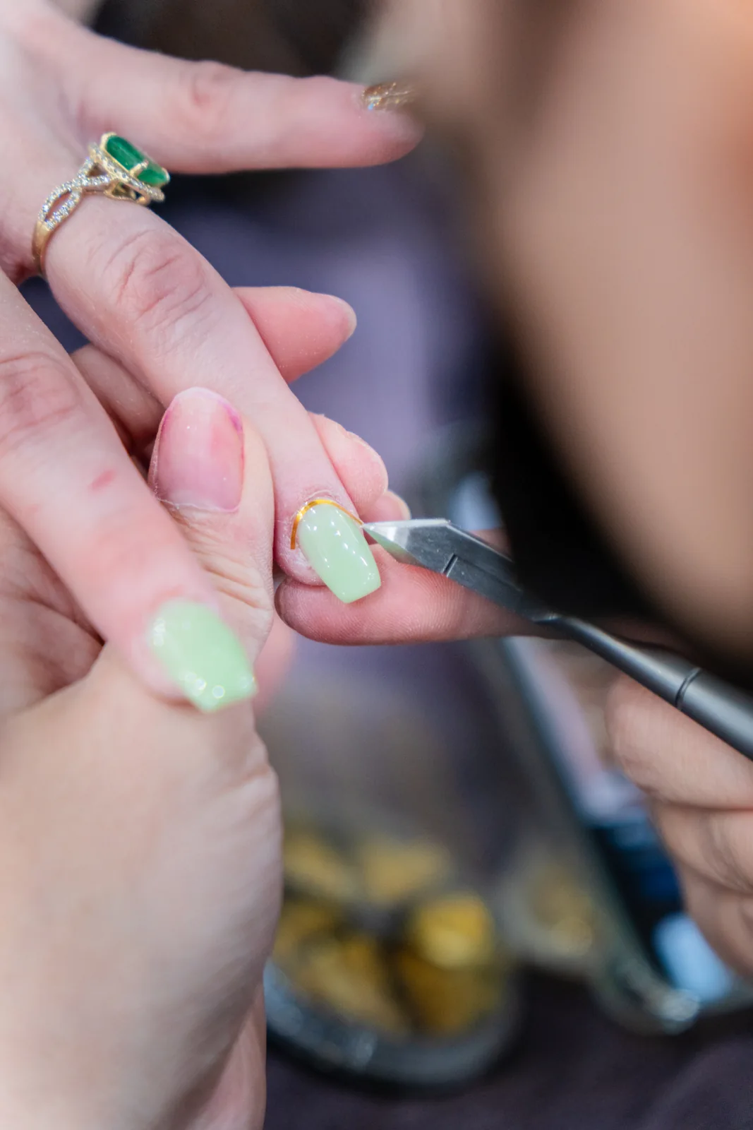 A fine brush adding gold detail to mint green nails
