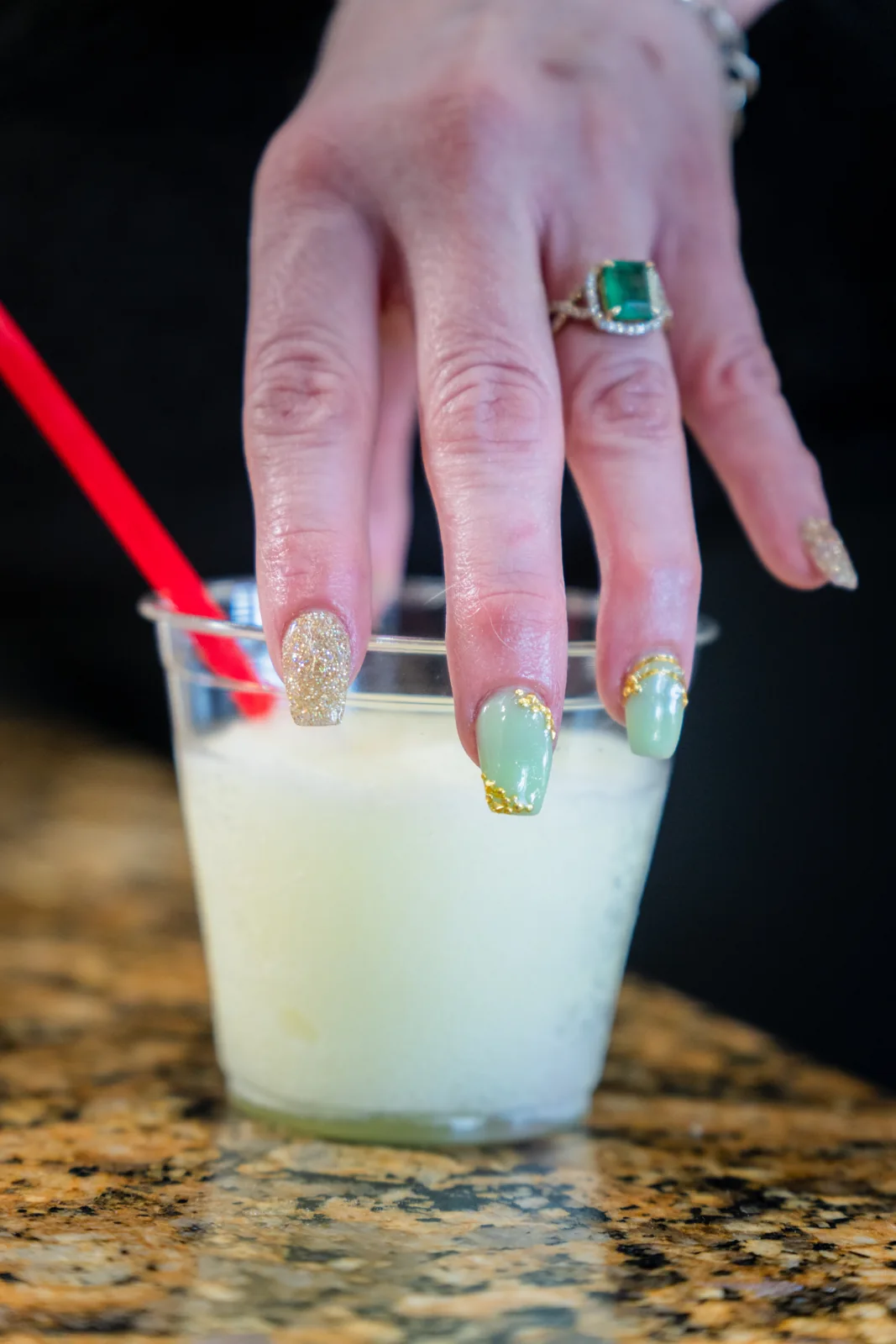 Mint green and gold nails holding a drink